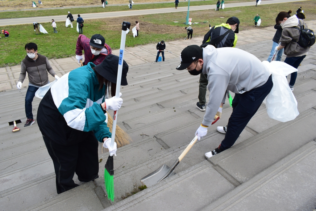 石狩川沿いの堤防を掃除する山本ビル社員の写真